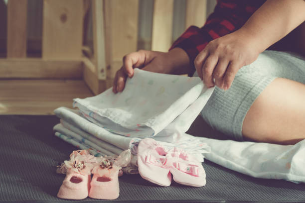Close Up Girl hands folding diapers to baby. Preparing to store cloth and baby shoes. Vintage style. stock photo