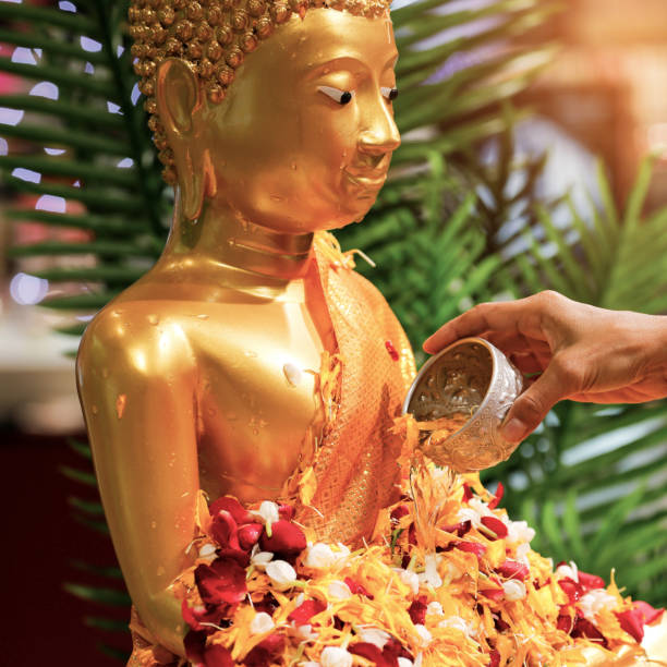 Close up hand of woman sprinkle water onto a gold buddha image on Songkran Festival Day at Thailand. stock photo