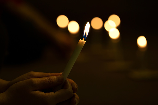 Close up hands  lighting candle vigil in darkness.Concept of light of hope., worship, prayer.soft focus