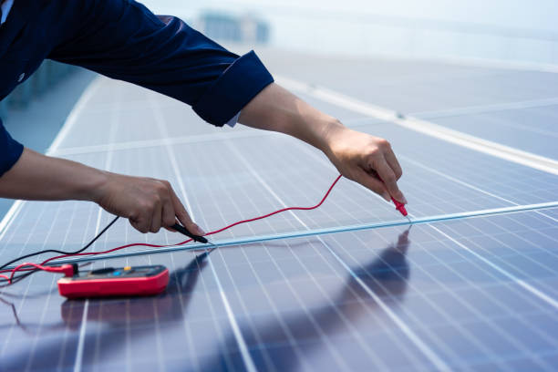 Close up hands of the engineers are using electrical measuring instruments on the solar cell plan. stock photo