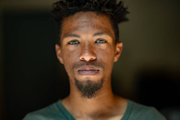 Close up Headshot Portrait of young mixed race male face with green eyes facial hair and rasta hair stock photo