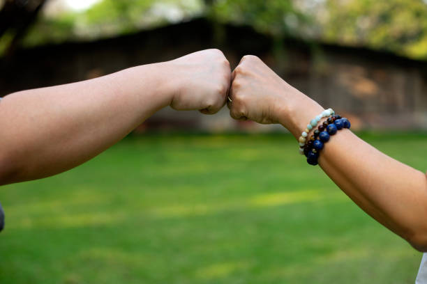 Close up image of two hand fist bump at the outdoor area green background stock photo