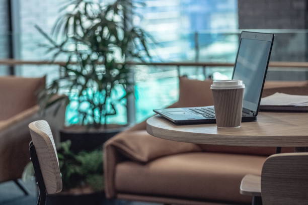Close up image of unoccupied seats in an office environment with laptop computer and coffee cups with no people. stock photo