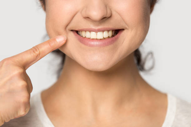 Close up Indian girl pointing finger to healthy smile Close up Indian girl pointing finger to healthy smile isolated on grey studio background, straight white teeth, satisfied client customer recommending dental whitening service, beauty and hygiene healthy skin exercise stock pictures, royalty-free photos & images