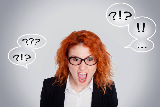 Close up isolated portrait of young annoyed angry woman. Negative human emotions face expressions. Isolated portrait on a gray background with question marks and exclamation marks stock photo