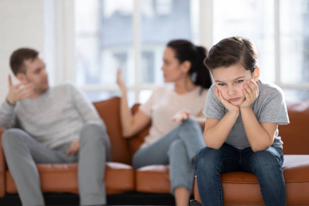 Close up little boy suffering from parents conflict. Close up little boy suffering from parents conflict sitting at couch. Sad son frustrating hear mother and father fighting arguing and bad situation, family conflict, divorce. couple divorce photos stock pictures, royalty-free photos & images