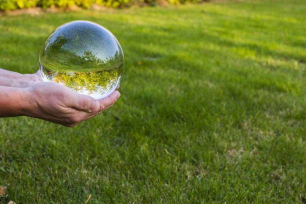 Close up macro view of hand holding crystal ball with inverted image of green natural landscape. Close up macro view of hand holding crystal ball with inverted image of green natural landscape. reentry stock pictures, royalty-free photos & images