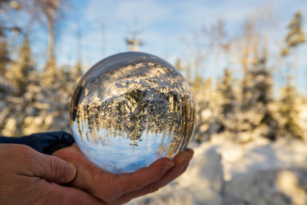 Close up macro view of hand holding crystal ball with inverted  image of winter natural landscape. Sweden. Close up macro view of hand holding crystal ball with inverted  image of winter natural landscape. Sweden. reentry stock pictures, royalty-free photos & images