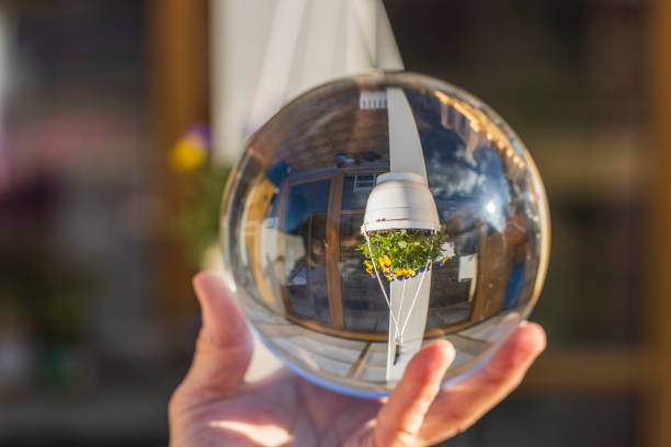 Close up macro view of hand holding crystal ball with inverted image of hanging basket  with yellow purple pansies. Sweden. Close up macro view of hand holding crystal ball with inverted image of hanging basket  with yellow purple pansies. Sweden. reentry stock pictures, royalty-free photos & images