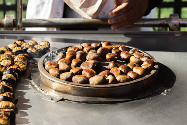 Close up man roasts chestnuts on the street Close up man roasts chestnuts on the street chestnut food stock pictures, royalty-free photos & images
