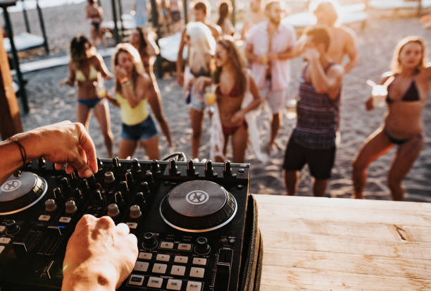 Close up of a DJ playing music on the beach party. Close up of unrecognizable DJ playing music on turntable during summer beach party. dj stock pictures, royalty-free photos & images