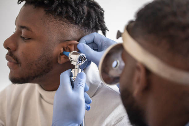 Close up of a doctor checking the ear of his male patient Close up of a male  doctor carefully holding the ear of his patient to establish a clearer view of the inside of his ear, to see if he requires hearing aids at a modern clinic hearing aids stock pictures, royalty-free photos & images