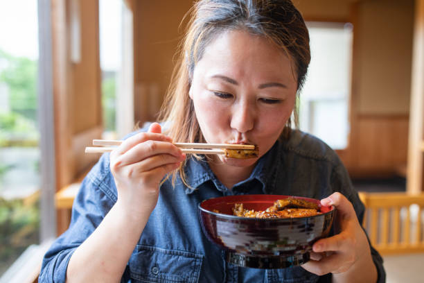 Close up of a Japanese woman eating Unagi Don (Eel rice bowl) stock photo