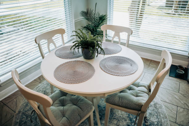 Close up of a small table and four chairs in an eat in kitchen with a tile floor stock photo