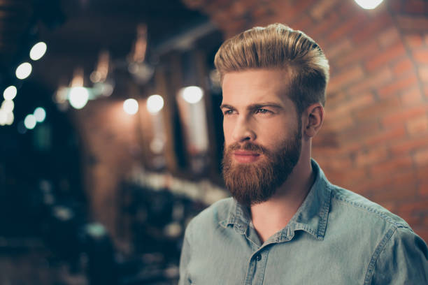 Close up of a stunning look of a red bearded guy with trendy hairdo in a barber shop. Looking so fashionable and confident Close up of a stunning look of a red bearded guy with trendy hairdo in a barber shop. Looking so fashionable and confident beard stock pictures, royalty-free photos & images