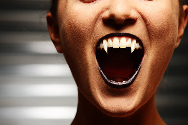 Close up of a vampire woman's mouth Close up of a vampire woman's mouth over dark background vampire stock pictures, royalty-free photos & images