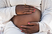istock Close up of african pregnant woman holding her belly - Focus on hands 1340020013