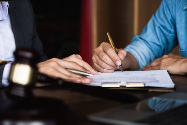 Close up of an executive hands holding a pen and indicating where to sign a contract at office stock photo