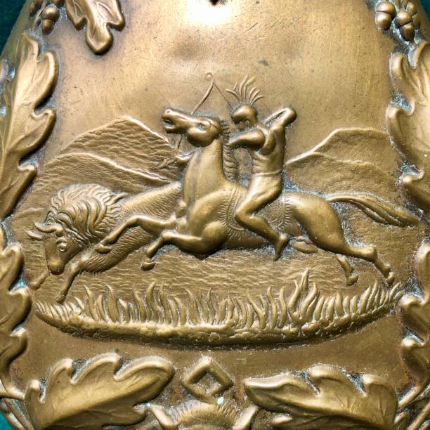 Close up of antique American copper powder flask A close up of 19th century American powder flask bas relief scene of a Native American man hunting a bison (Buffalo). The flask is copper. buffalo shooting stock pictures, royalty-free photos & images