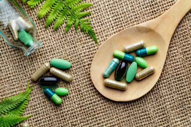 Close up of assorted capsules and pills into wooden spoon on a rustic background stock photo