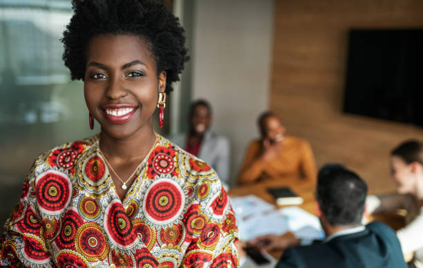close up of beautiful young smiling professional black african business woman, coworkers hold a meeting in background - origem africana imagens e fotografias de stock