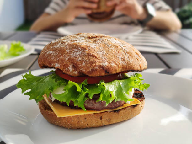 Close up of big tasty burger with green salad and fluffy bun stock photo
