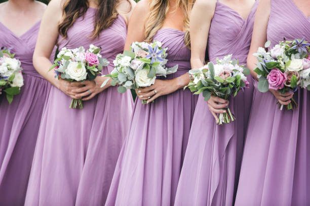 Close up of bridal party with floral bouquets Bridesmaids in pink and vioilet dresses holding floral arrangements. CLose up of bridal party with bouquets. bridesmaid dresses stock pictures, royalty-free photos & images