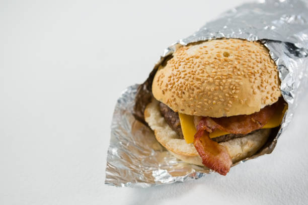 Close up of burger wrapped in foil paper Close up of burger wrapped in foil paper on table burger wrapped in paper stock pictures, royalty-free photos & images