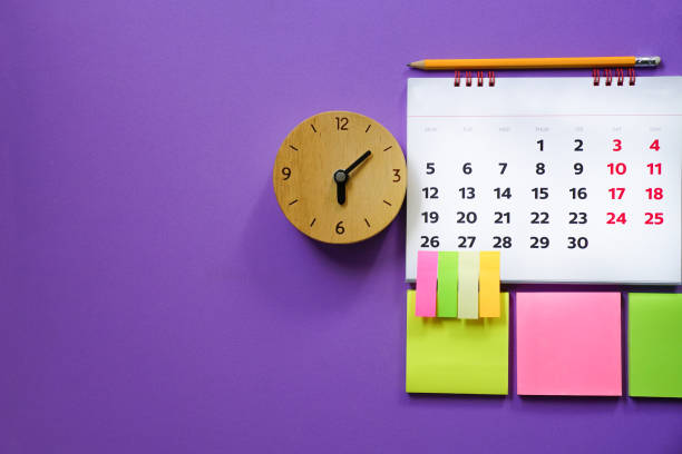 close up of calendar and alarm clock on the purple  table, planning for business meeting or travel planning concept stock photo