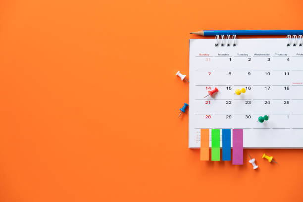 close up of calendar on the orange table background, planning for business meeting or travel planning concept close up of calendar on the orange table background, planning for business meeting or travel planning concept holiday calendars stock pictures, royalty-free photos & images