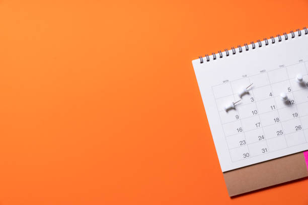 close up of calendar on the orange table background, planning for business meeting or travel planning concept stock photo