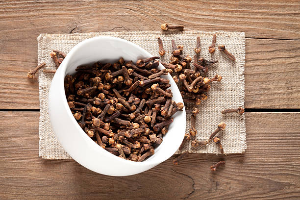 Close up of cloves in cup on wooden table stock photo