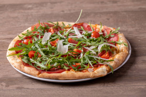 primo posto di deliziosa pizza fresca italiana con prosciutto, rucola, pomodoro e parmigiano - piadina bresaola foto e immagini stock