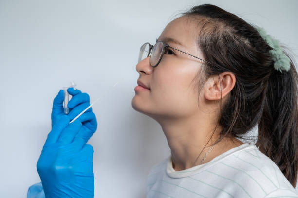 Close up of doctor hands trying to taking a nasal swab from Asian woman for testing diagnosis of covid-19 infection. stock photo