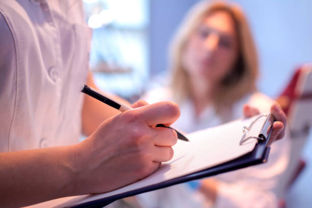 Close up of doctor writing on a medical chart. stock photo
