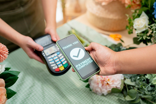 Close up of easy payment by credit card or smartphone application Greenhouse workers selling pottered flowers.Contactless payment with credit card customer at counter using QR code contactless payment