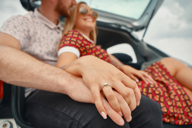 Close up of engaged couple holding hands with diamond ring stock photo