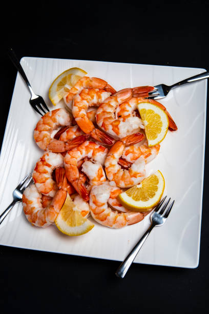 Close up of fresh shrimp on a plate with forks and lemon slice stock photo