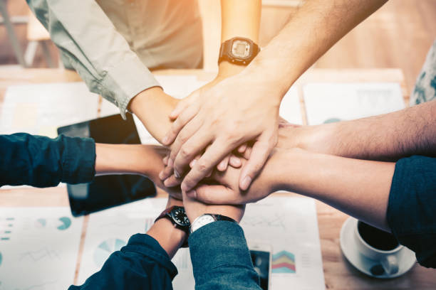 Close up of  group of business people joining their hands together in unity. Close up of  group of business people joining their hands together in unity. dedication stock pictures, royalty-free photos & images