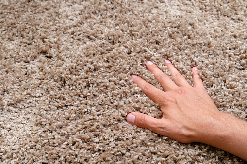 Close up of hand touching soft carpet. Gentle and fluffy carpet between fingers.
