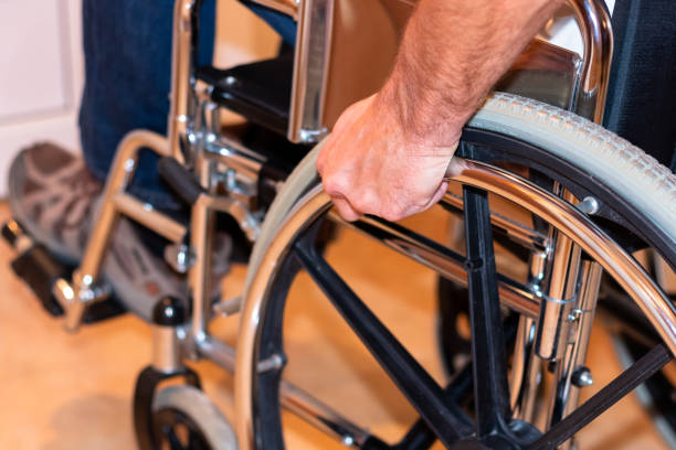 Close up of handicapped man's hand pushing wheel of wheelchair stock photo