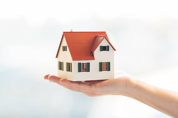 close up of hands holding house or home model stock photo