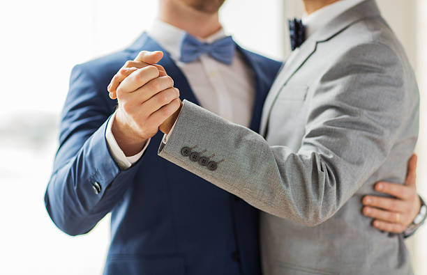 close up of happy male gay couple dancing people, homosexuality, same-sex marriage and love concept - close up of happy male gay couple holding hands and dancing on wedding fiancé stock pictures, royalty-free photos & images