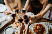 istock Close up of happy young friends having fun and toasting and celebrating with red wine during party 1155378553