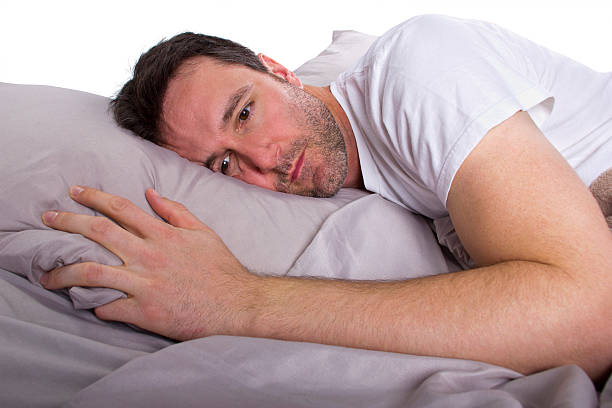 Close Up of Male Insomniac Unable to Sleep in Bed stock photo
