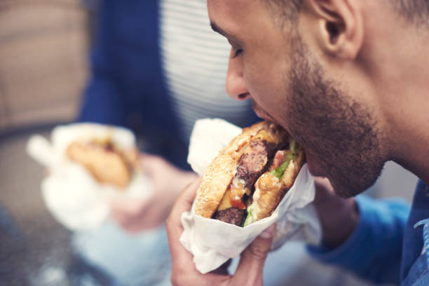 close-up do homem comendo cheeseburger - pessoas comendo carne - fotografias e filmes do acervo