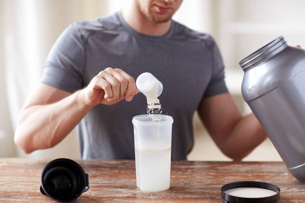 close up of man with protein shake bottle and jar stock photo