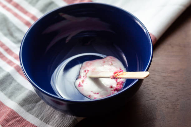 Close Up of Melted Ice Cream Popsicle In A Blue Ceramic Bowl On A Table stock photo