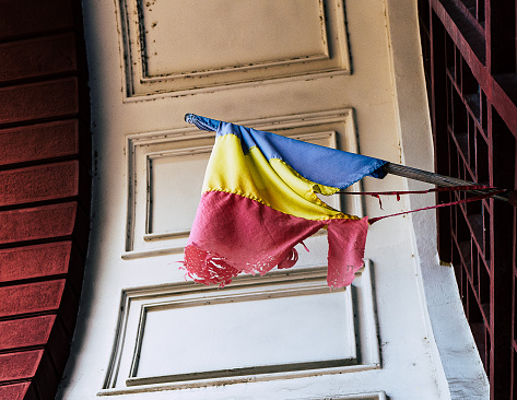An old Romanian flag is torn and badly damaged while on its flagpole. Room for copy space.