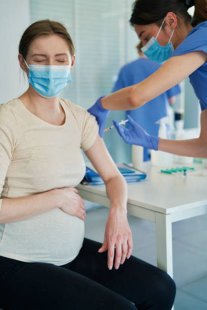 Close up of pregnant woman taking a vaccination stock photo